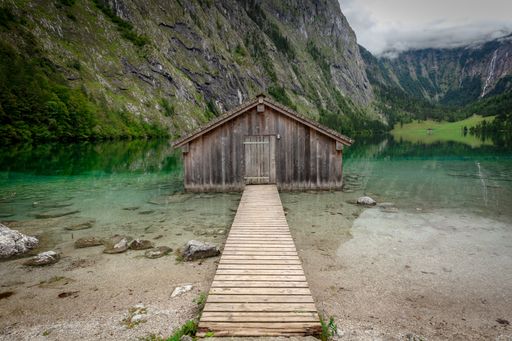 Panoramic view traditional old wooden boat house at scenic Lake Obersee on a beautiful day with blue sky and clouds in summer, Bavaria, Germany