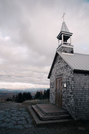 A vertical shot of a small stone chapel on a gloomy day