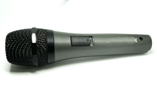A closeup of a black colored microphone on a white surface