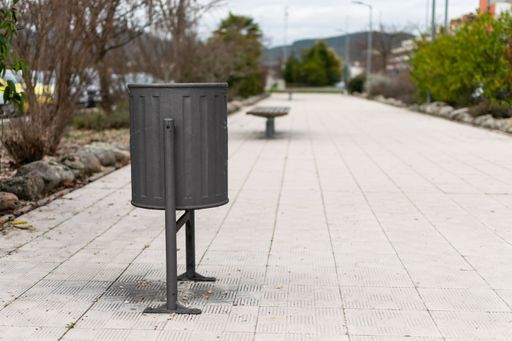 A gray painted metal trash can in the park