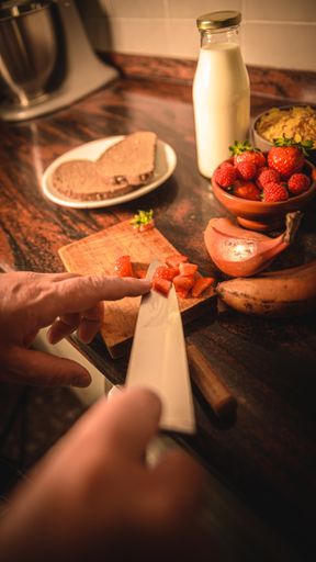 A closeup of hands cutting strawberries into small pieces