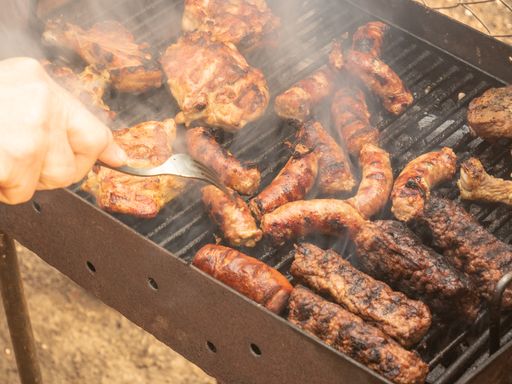 A close-up of hands grilling sausages