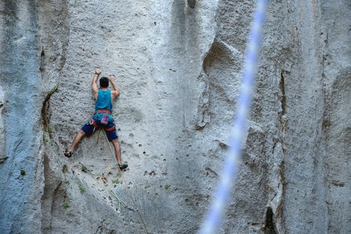 A man in a blue shirt rock climbing