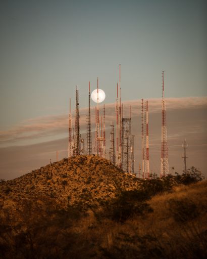 A vertical shot of a full moon rises over the radio towers on South Mountain in Phoenix, Arizona
