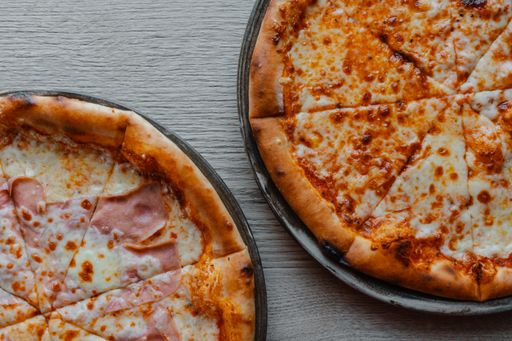 vertical photo of multiple pizzas on table