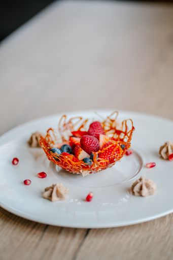 A closeup of fresh decorated strawberries and raspberries for dessert on a white plate