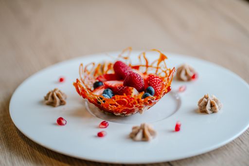 A closeup of fresh decorated strawberries and raspberries for dessert on a white plate