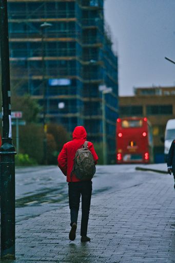 A back view of a man in the rain with a nice bright colored red coat