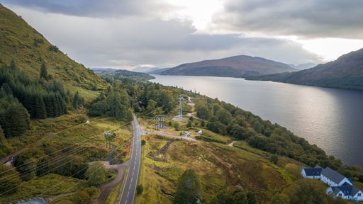 An aerial shot of an asphalt road on a mountain near the lake