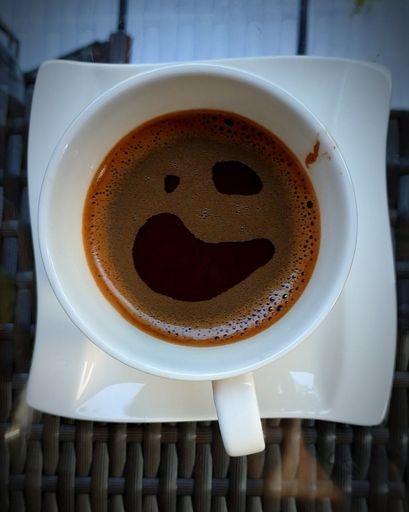 A top view of a cup of brown coffee on a saucer.
