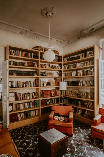 A vertical shot of a vintage room with bookshelves and orange armchairs