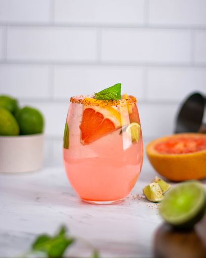 A vertical shot of the refreshing cocktail with the slices of grapefruit and lemon on white surface