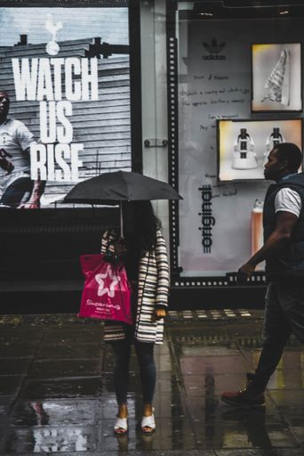 A photo of a woman standing with umbrella in the rainy day