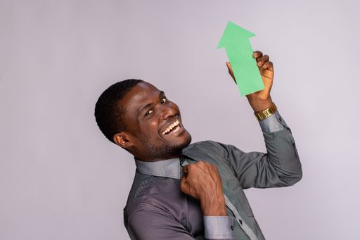 An excited African man holding a green arrow pointing upwards