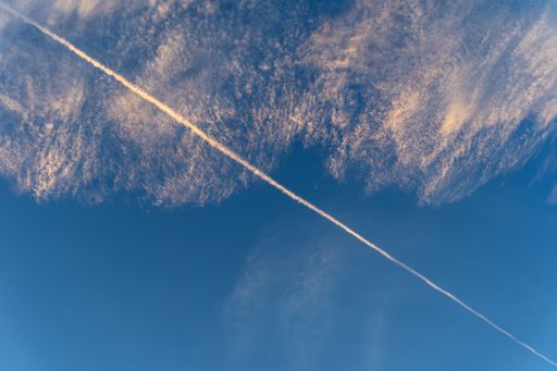 A mesmerizing shot of the blue sky and the peaceful white clouds left with an airplane mark