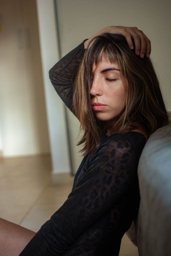 A vertical closeup of the beautiful girl in a black dress posing indoors.