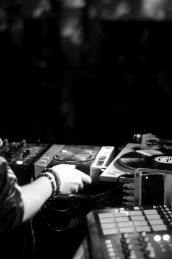 A grayscale shot of a disc jockey working on turntables