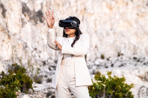 An elegant woman dressed in a white suit using a virtual reality goggles