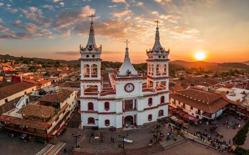 A beautiful Aerial View of San Cristobal Church in Mazamitla, Jalisco, Mexico at sunset orange sky
