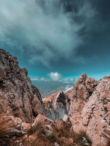 A vertical shot of rocky cliffs in the background of the sky. Perfect for wallpaper.