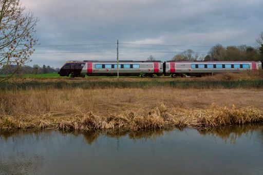 A gloomy day in Staffordshire, England with a train zooming by a small lake surrounded by dried grass