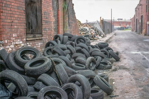 Pile of disused tyres next to ruins of warehouses in derelict street