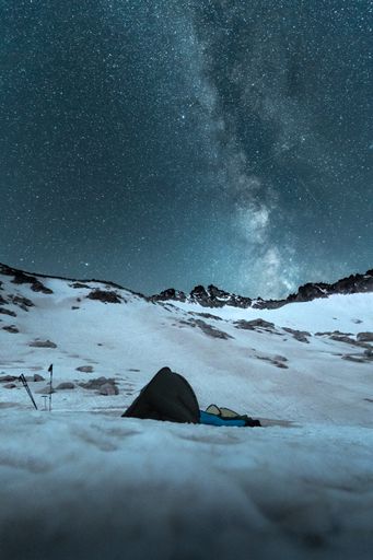 A vertical long exposure shot of a starry sky in a snowy field