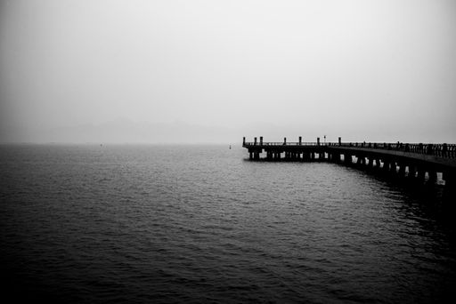 A grayscale shot of a pier on the lake