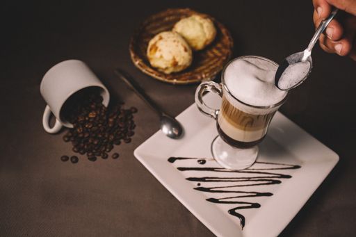 A closeup high angle shot of a table with coffee, spilled coffee beans, and cookies