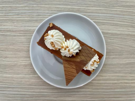 Top view of a delicious Toffee cake with cream and piece of chocolateon a white plate