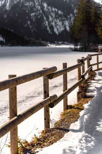A vertical shot of a wooden fence in a snow-covered field in Reutte, Austria