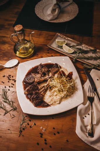 A vertical closeup shot of a plate full off food with an oil pot and cutlery on the table