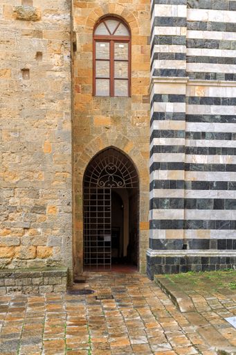 A vertical shot of the entrance of an old building with an arched door and window