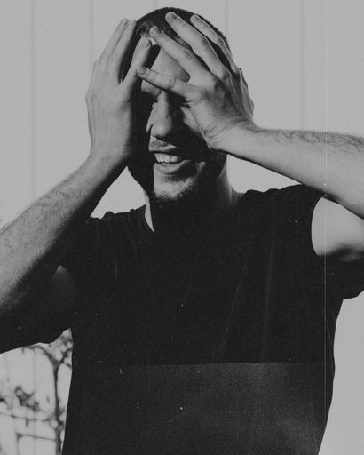 A grayscale vertical shot of a depressed male holding his head with his hands