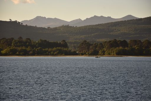 A landscape view of a lake surrounded by mountains on a sunny day