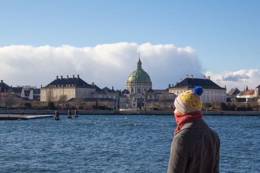 A female in winter clothes standing in front of the Frederiks church captured in Copenhagen, Denmark
