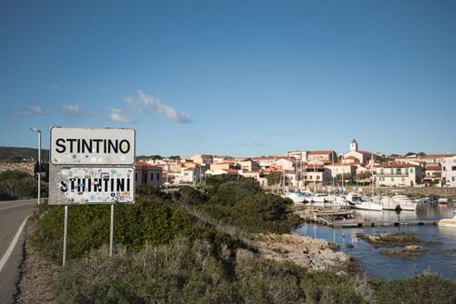 The Stintino city road sign, harbor and village in the background. Sardinia, Italy.