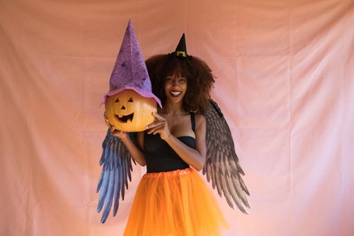 A young Afro-American woman in a witch costume with a pumpkin for Halloween party