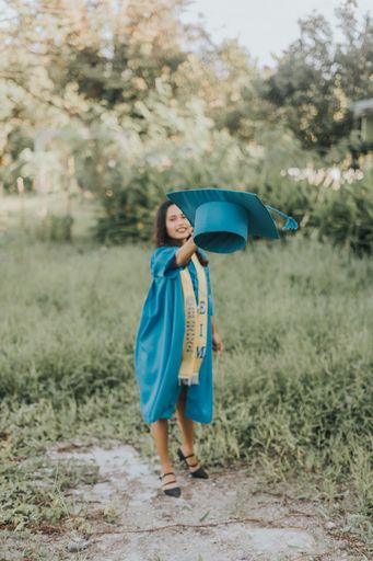 Amazing Portrait of a Pretty Asian Filipino Woman in her Graduation Cap and Gown while Throwing his Graduation up close to the Camera on University Ca