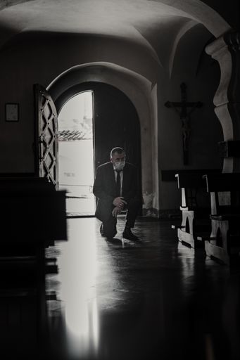 Man wearing mask and praying at church in Lithuania during panemic situation with COVID-19.