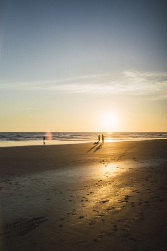 A beautiful seascape of the sunset over the coastline and some people walking