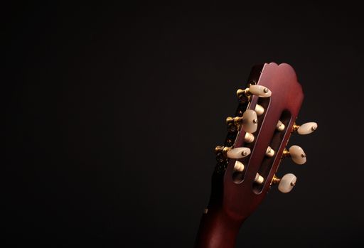 A closeup shot of a head of a bass guitar neck isolated on a black background