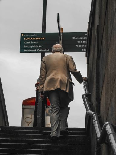 A vertical shot of a man in a suit from behind walking up the stairs in London