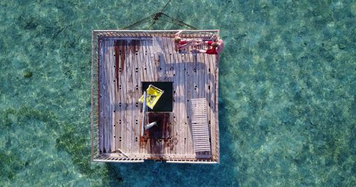 An aerial top view of a couple on a wooden port on Rasdhoo Island, the Maldives