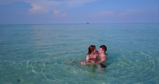 A loving couple hugging and swimming in the ocean of Rasdhoo island, Maldives