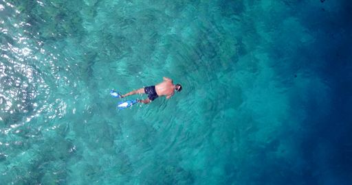 An aerial top view of a diver swimming in the ocean in Rasdhoo Island, the Maldives