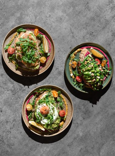 A top view of three plates with different types and portions of breakfast on the table