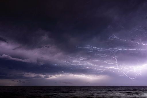 A dramatic purple sunset sky with thunderstorm and lightning