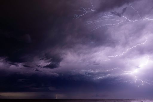A dramatic purple sunset sky with thunderstorm and lightning