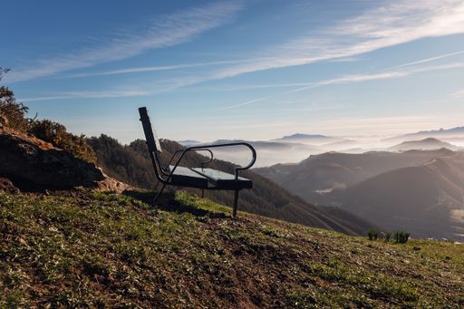 A closeup shot of a bench on the top of the hill on the background of mountains